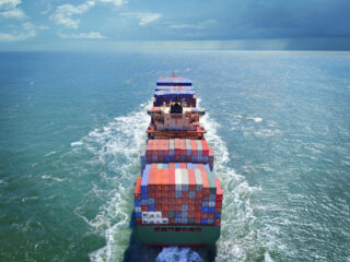 Aerial view of freight ship with cargo containers on the sea. See similar photos: :  http://www.oc-photo.net/FTP/icons/cargo.jpg
