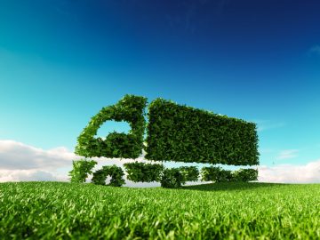 Eco friendly transportation concept. 3d rendering of green green truck icon on fresh spring meadow with blue sky in background.