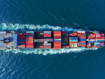 Aerial view Top speed with beautiful wave of container ship full load container with crane loading container for logistics import  export or transportation concept background.